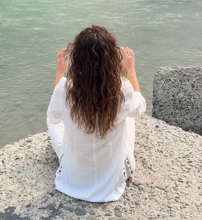 Martina di spalle, seduta in meditazione sulla riva del Gange